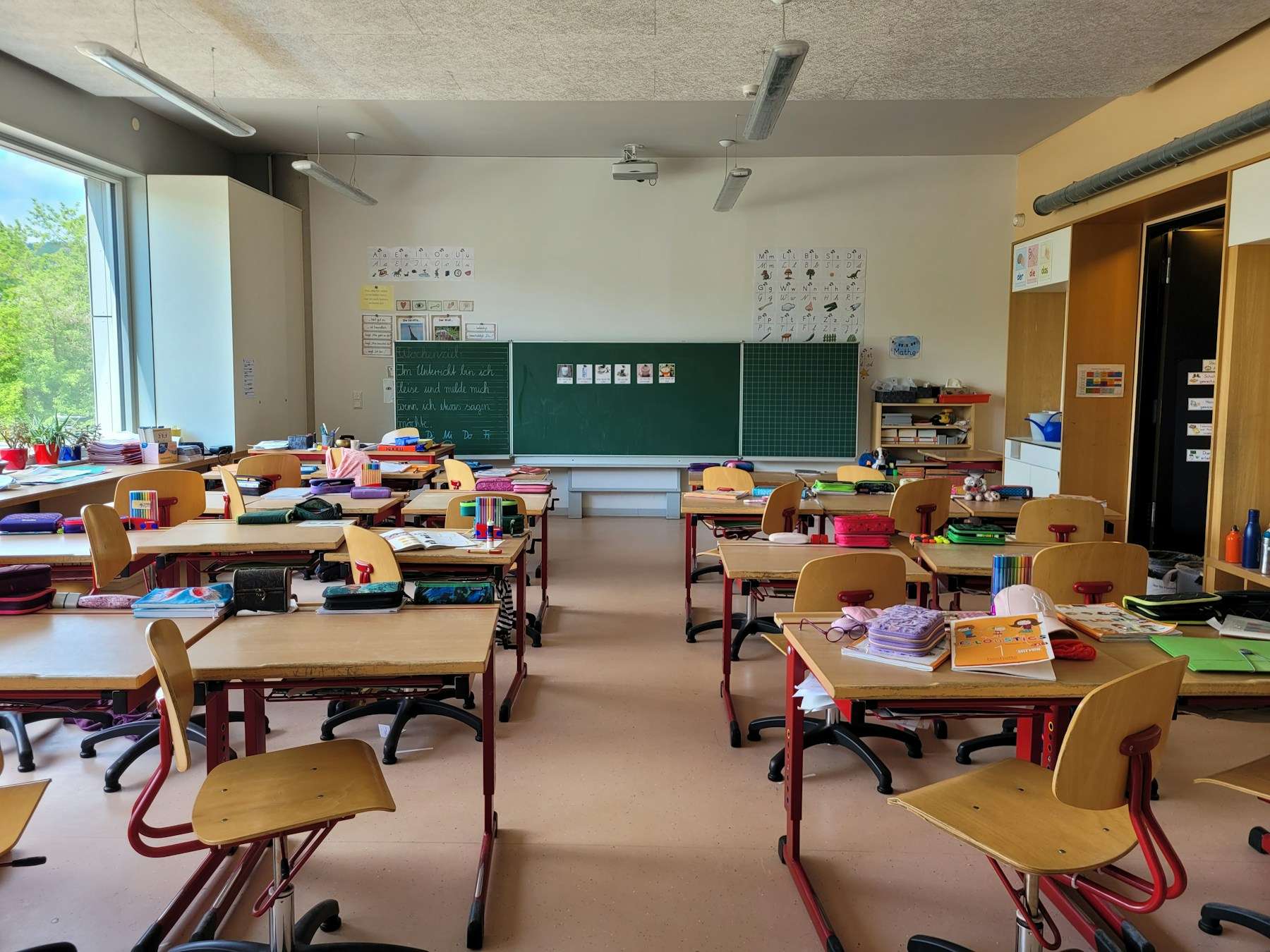 Klassrum med bänkar, stolar och tavla